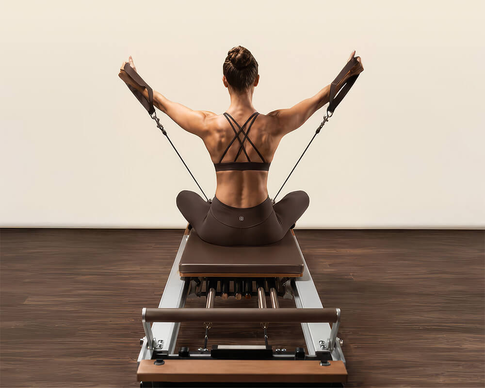 Trainierte Frau übt auf einem Reformer